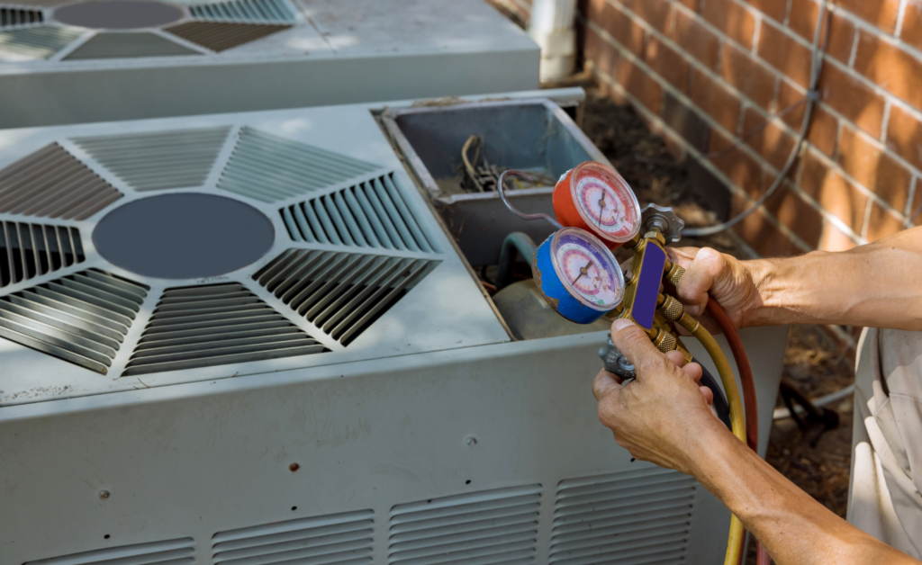 View of the hands of an HVAC mechanic holding a red and blue testing unit.