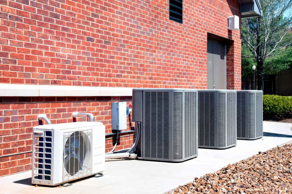 Three commercial air conditioning units situated on the side of a brick building.